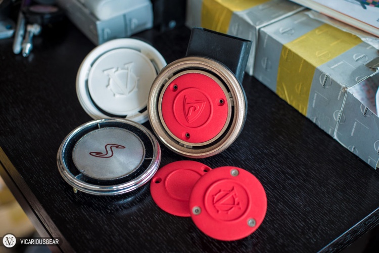 The various parts all together. Clockwise from upper left: White plastic prototype, stainless ring, red plastic center caps, original "S"vent.